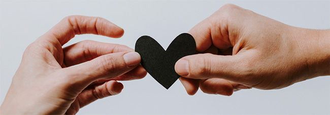 Two hands holding a heart-shaped piece of paper